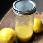 vegan lemon vinaigrette in a baller jar with two lemons on the side