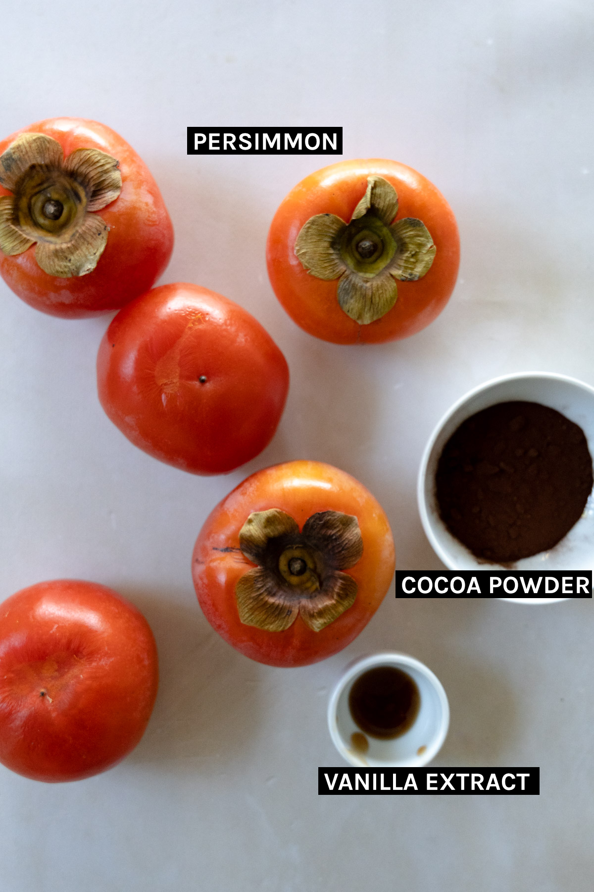 5 persimmons, cocoa powder and vanilla extra in white bowls