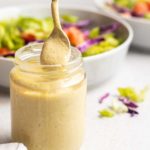vegan italian dressing in a jar with a salad in the background
