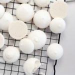 white vegan meringues on a black wire cooling rack