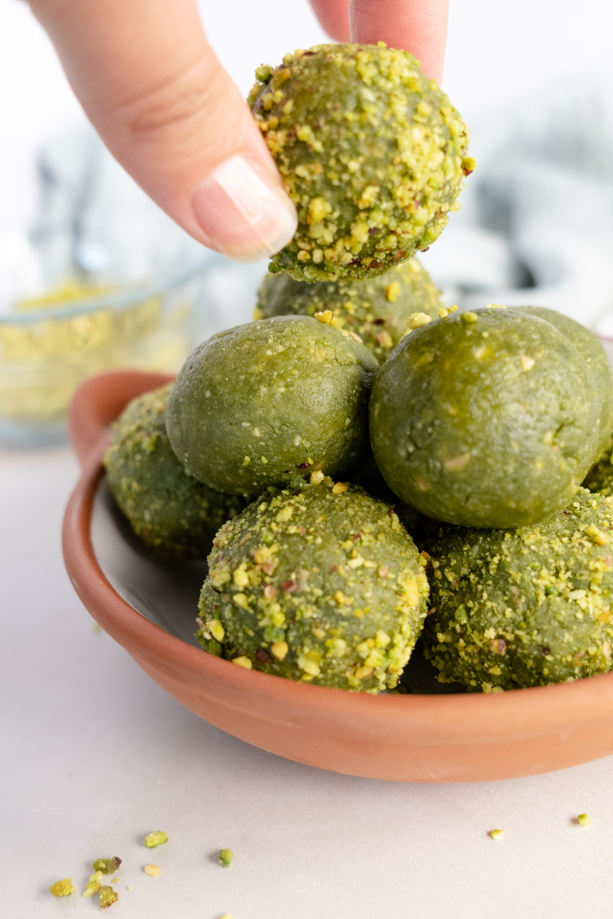 matcha balls in a brown bowl with one held by a female hand