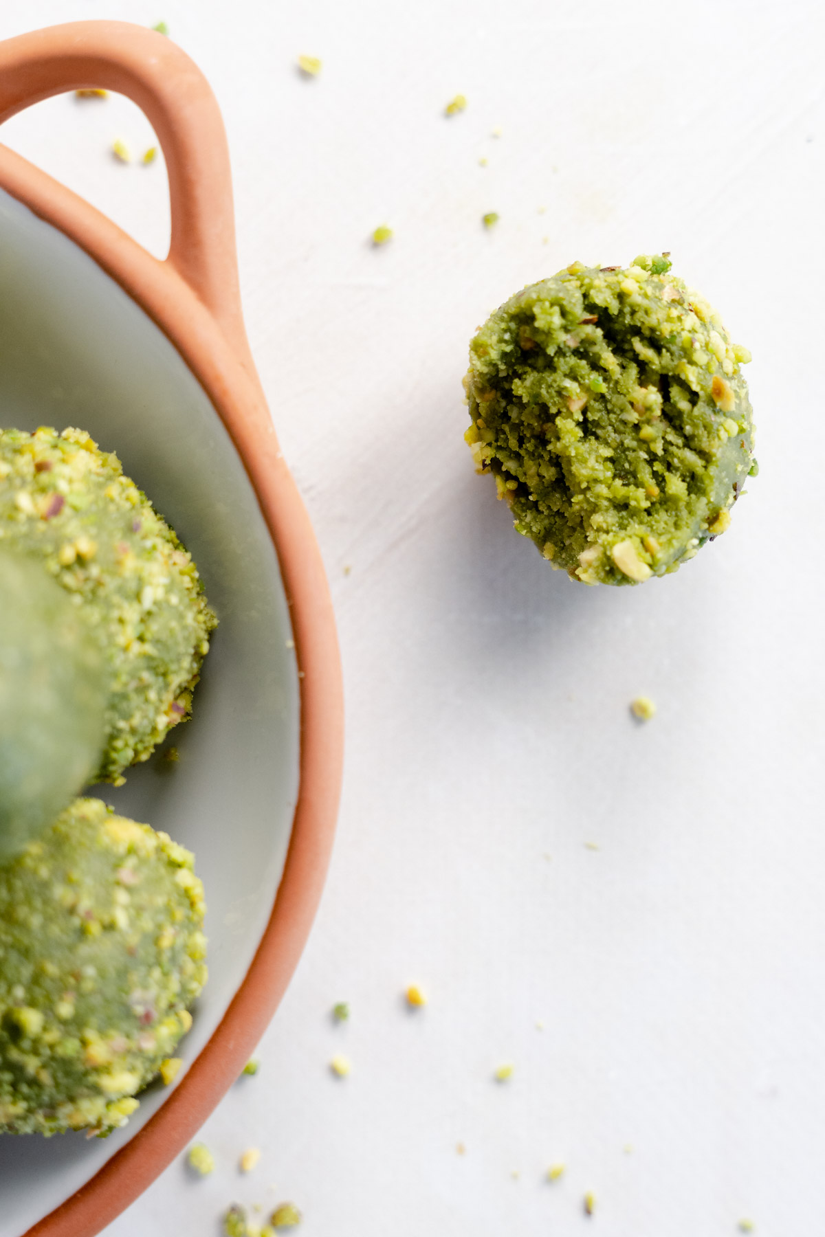 a matcha bliss ball with a bite on a white background