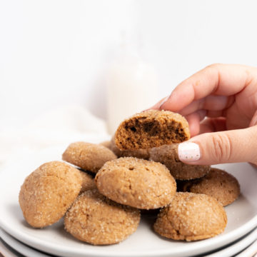vegan ginger cookies on a plate with a female hand holding one