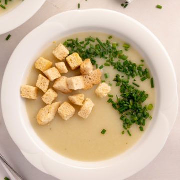 a bowl of potato and leek soup with croutons on top