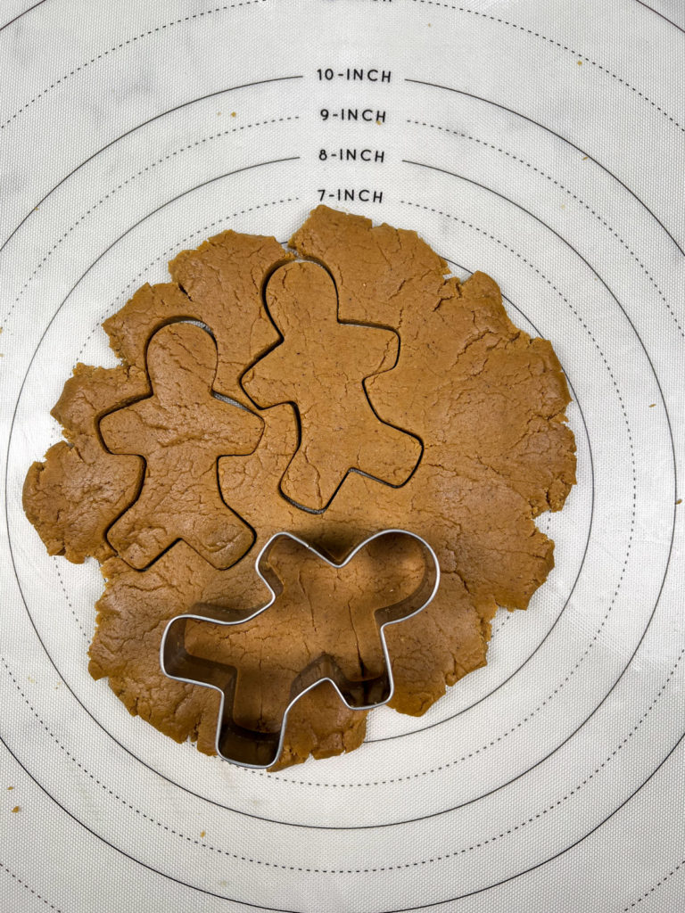 gingerbread man cookie cutter on dough with shapes cut out