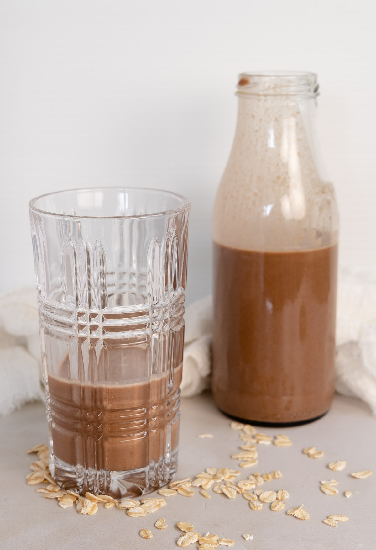 a glass cup and bottle filled with chocolate milk
