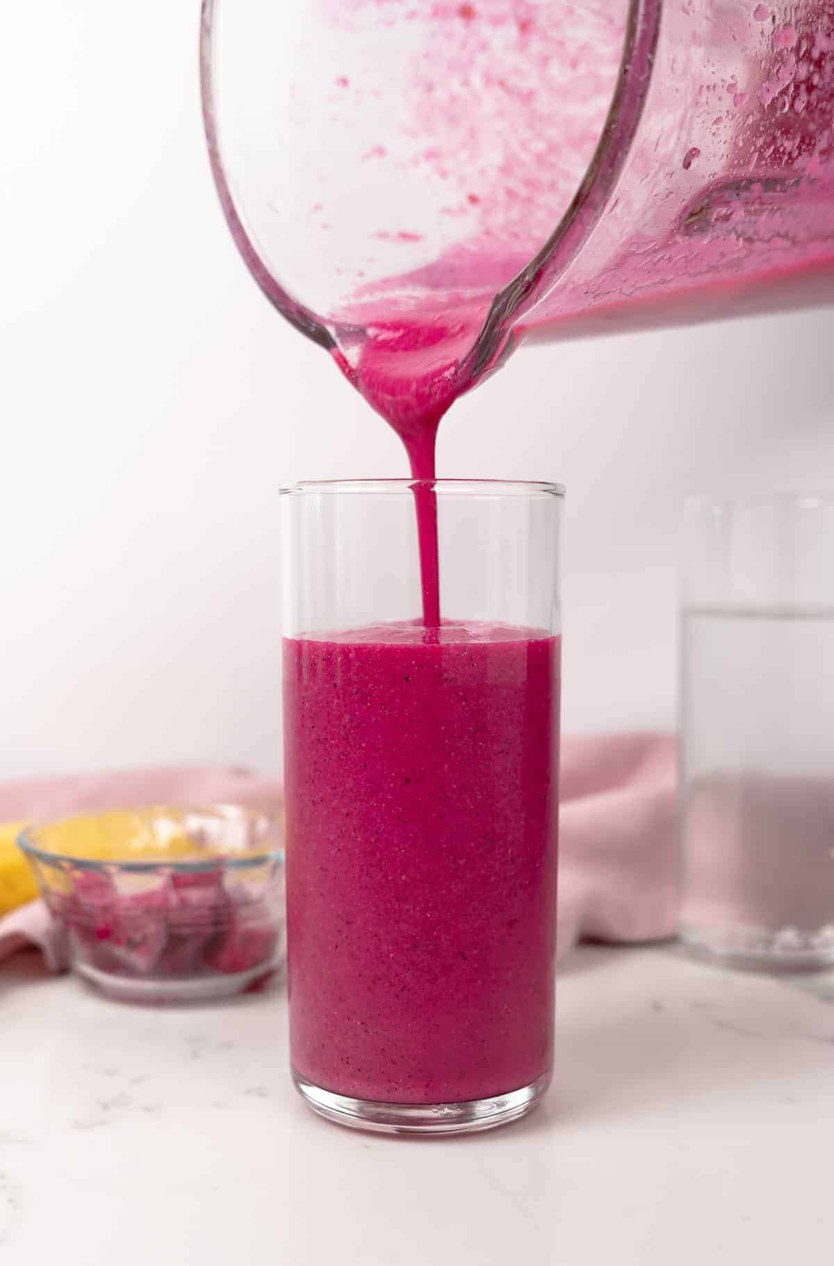 pouring pink smoothie into a cup