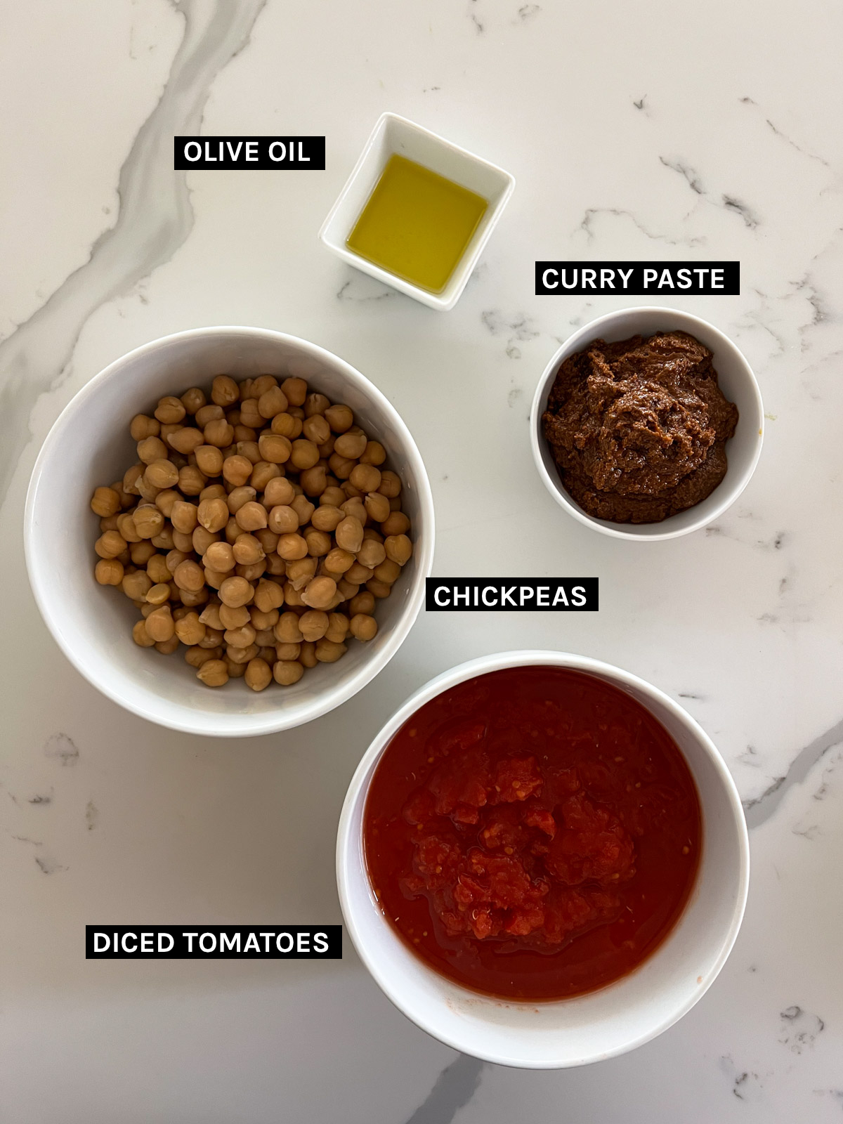 olive oil, curry paste, chickpea, diced tomatoes on a white benchtop