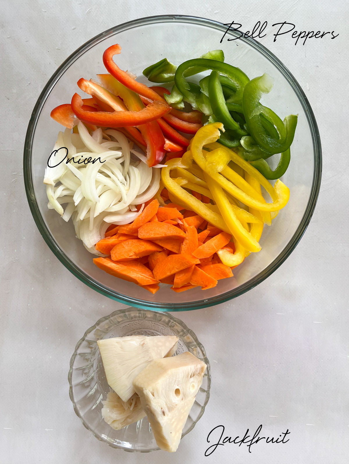 sliced bell peppers, onions and pieces of jackfruit in glass bowls