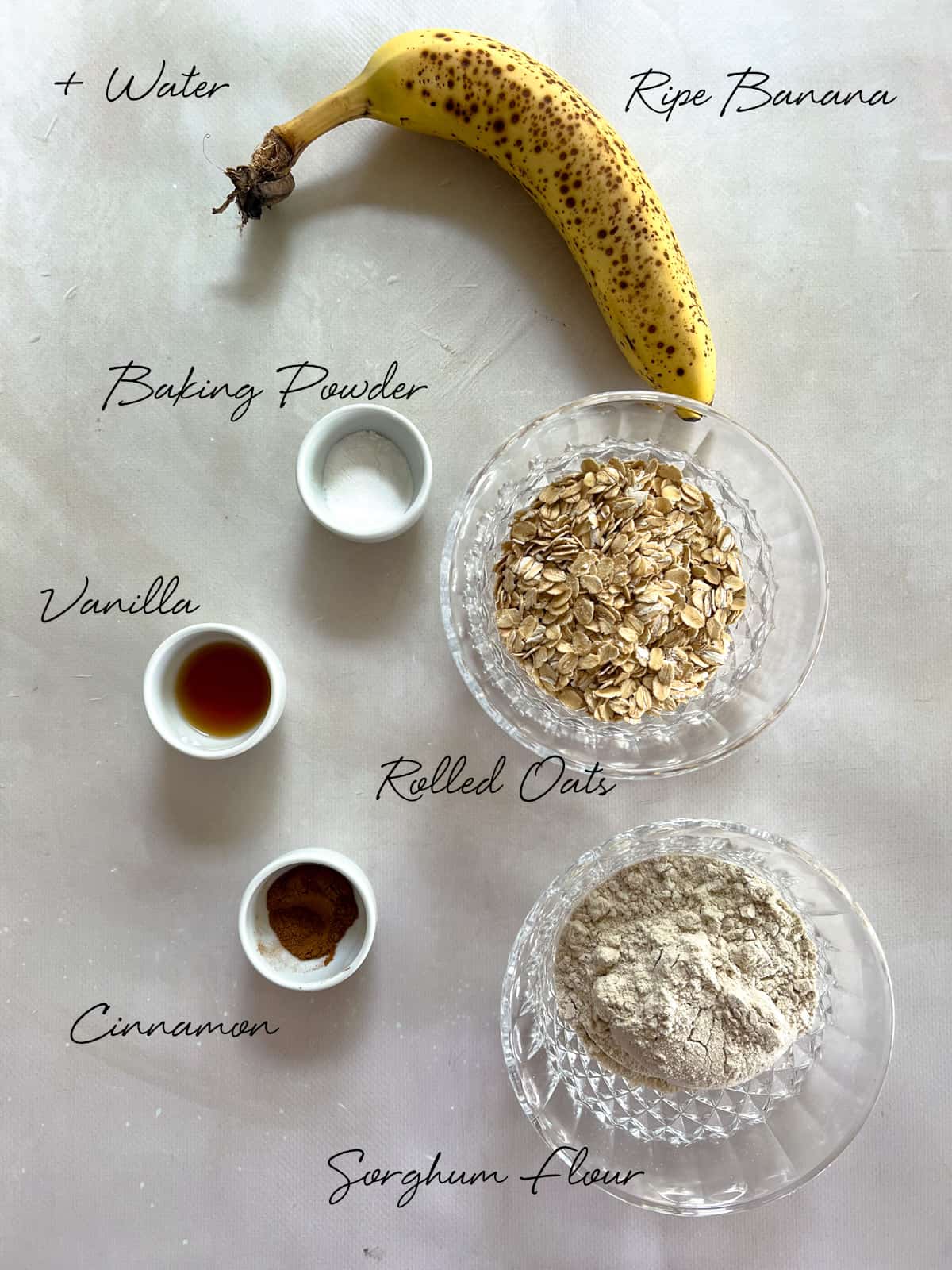 banana, baking powder, cinnamon, vanilla, rolled oats and sorghum flour laid out