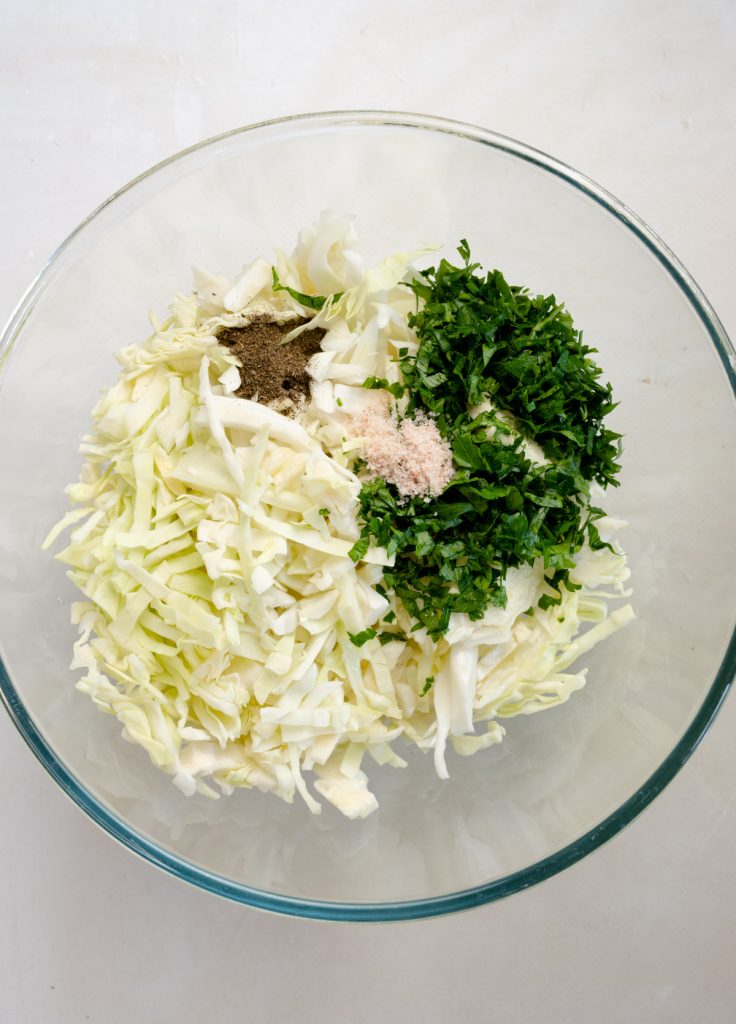 chopped cabbage, parsley, mint, salt in a glass bowl