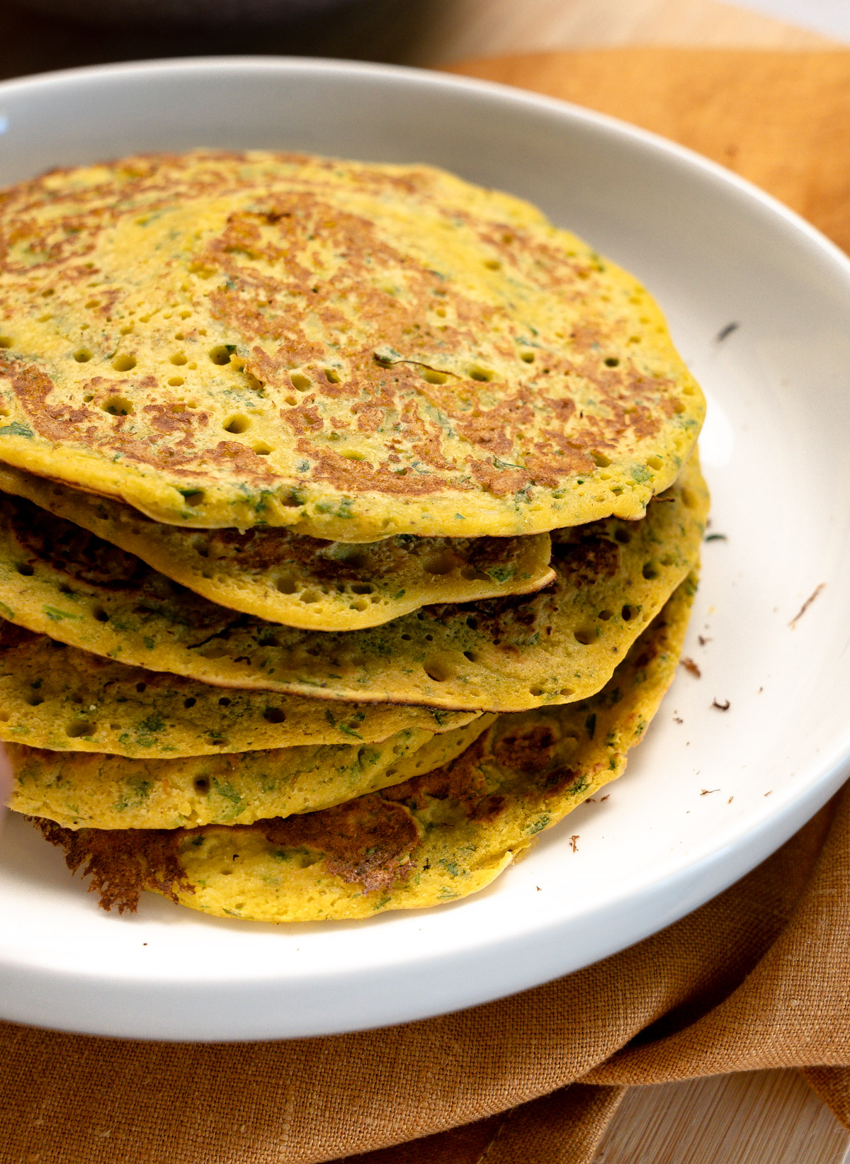 a stack on omelettes with green herbs through them in a white plate