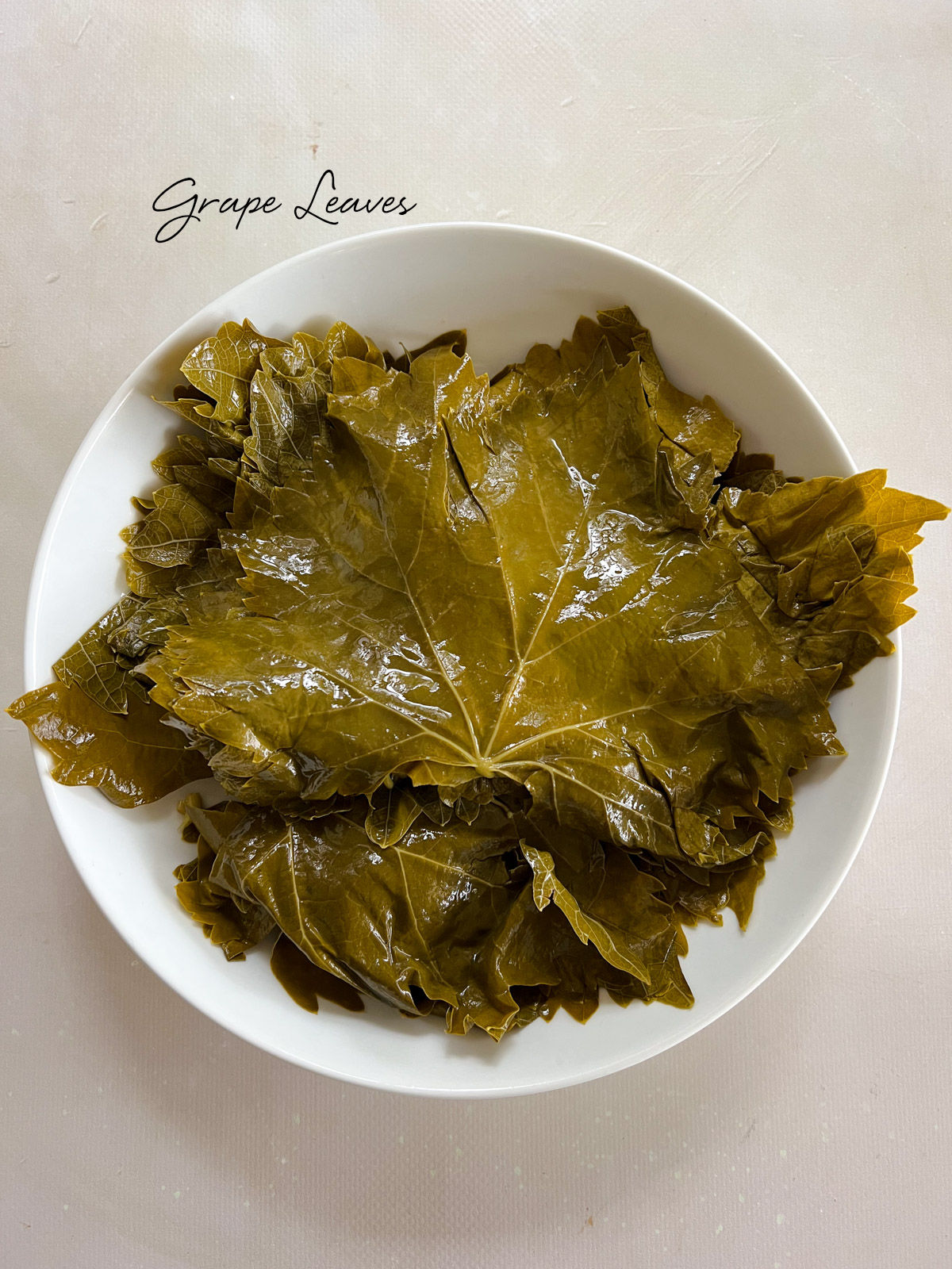 brined grape leaves laid flat in a white plate