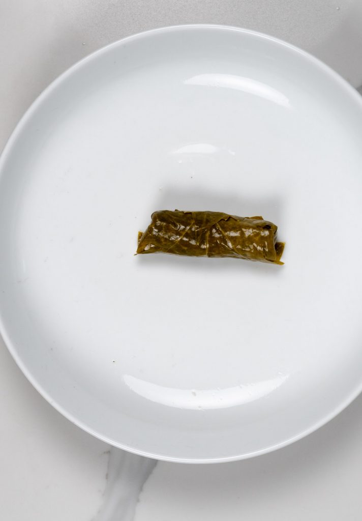 a rolled stuffed grape leave in a white plate