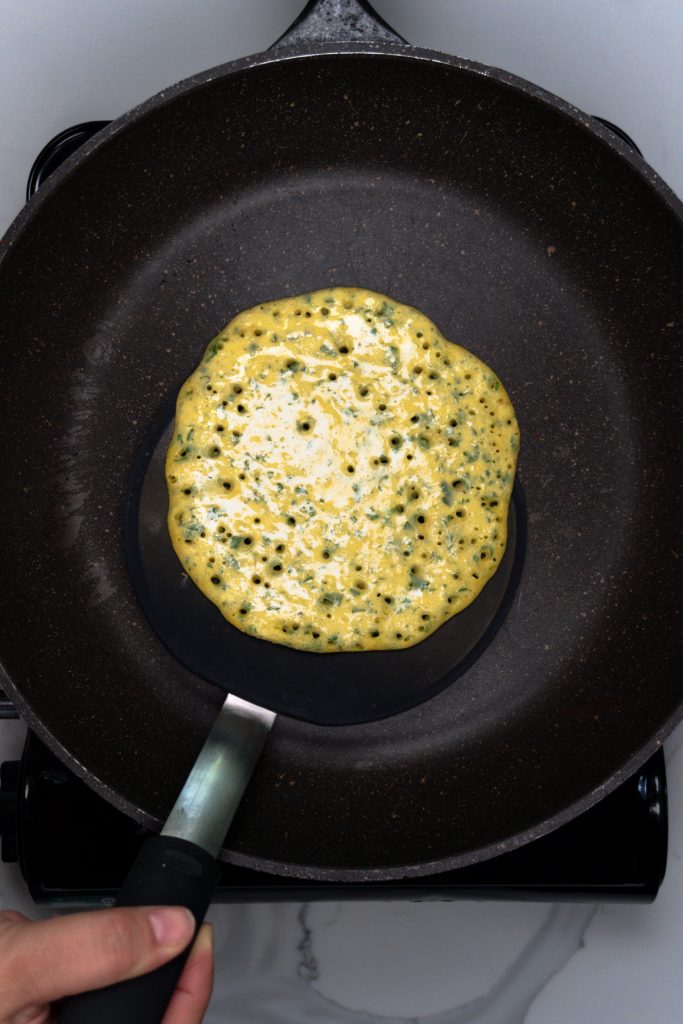 a spatula under the omelette ready to flip the first side