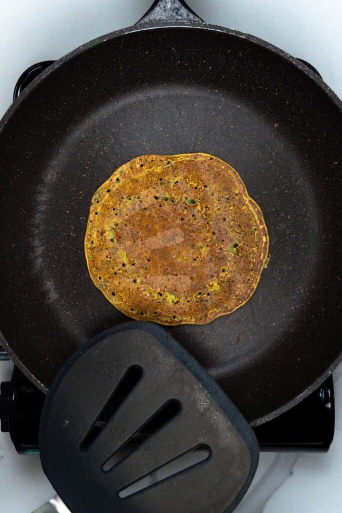 a flipped omlet in a frypan with a spatula next to it