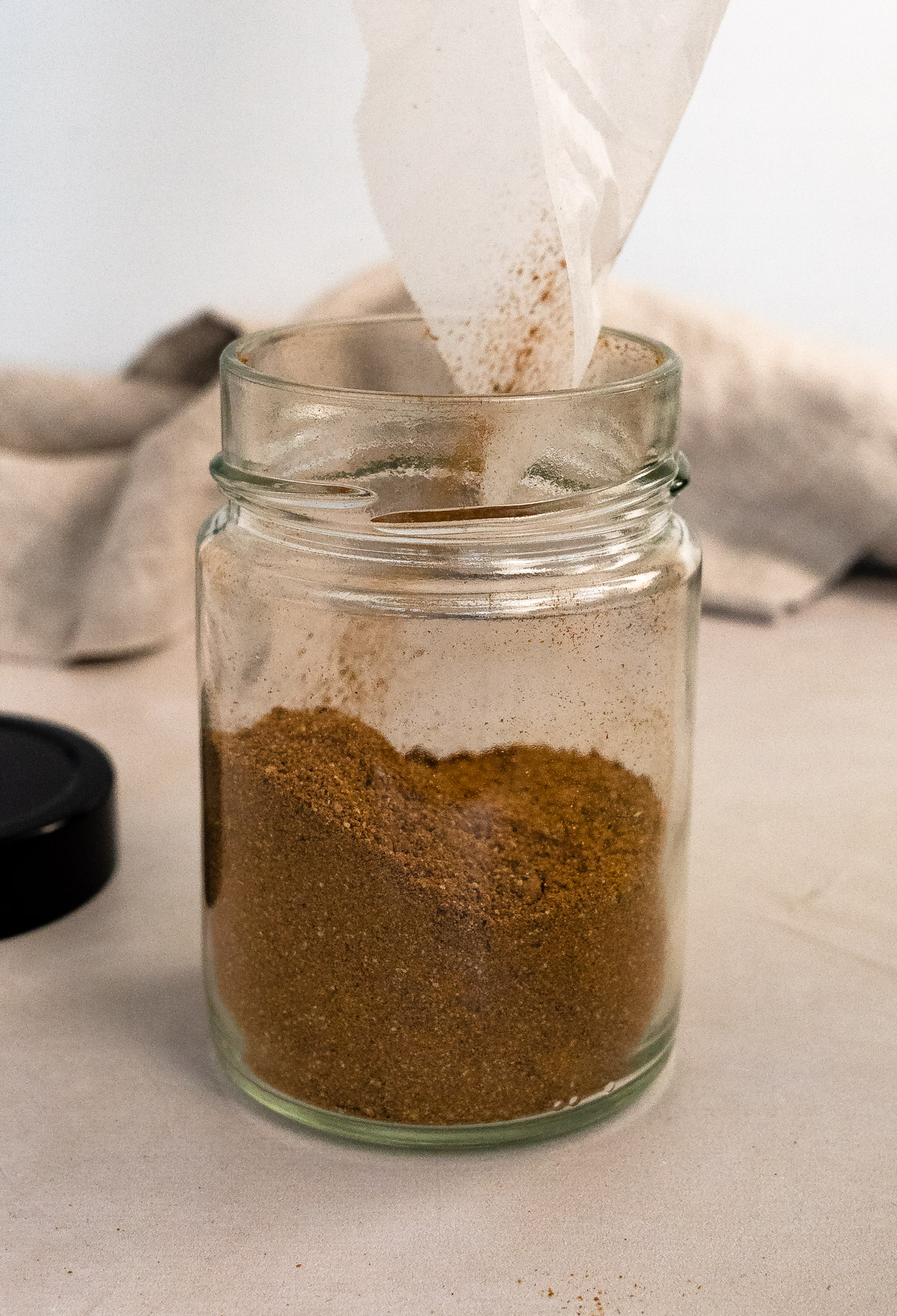pouring spices into a clear glass jar