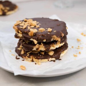 a stack of three rice cakes topped with chocolate, peanut butter and nuts