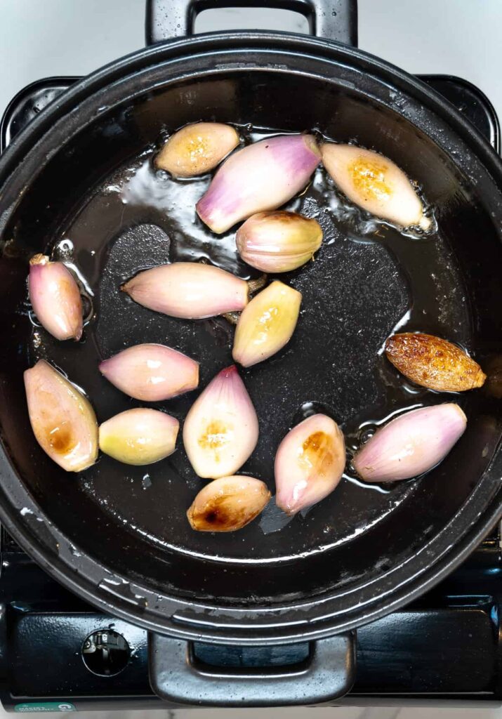 browning french shallots in a black pan
