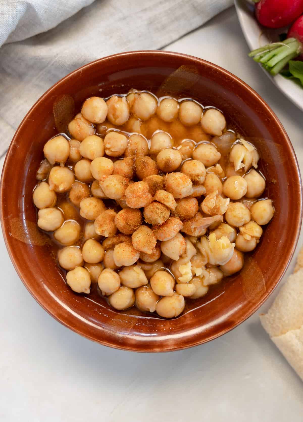 cooked garbanzo beans topped with spices in a brown bowl