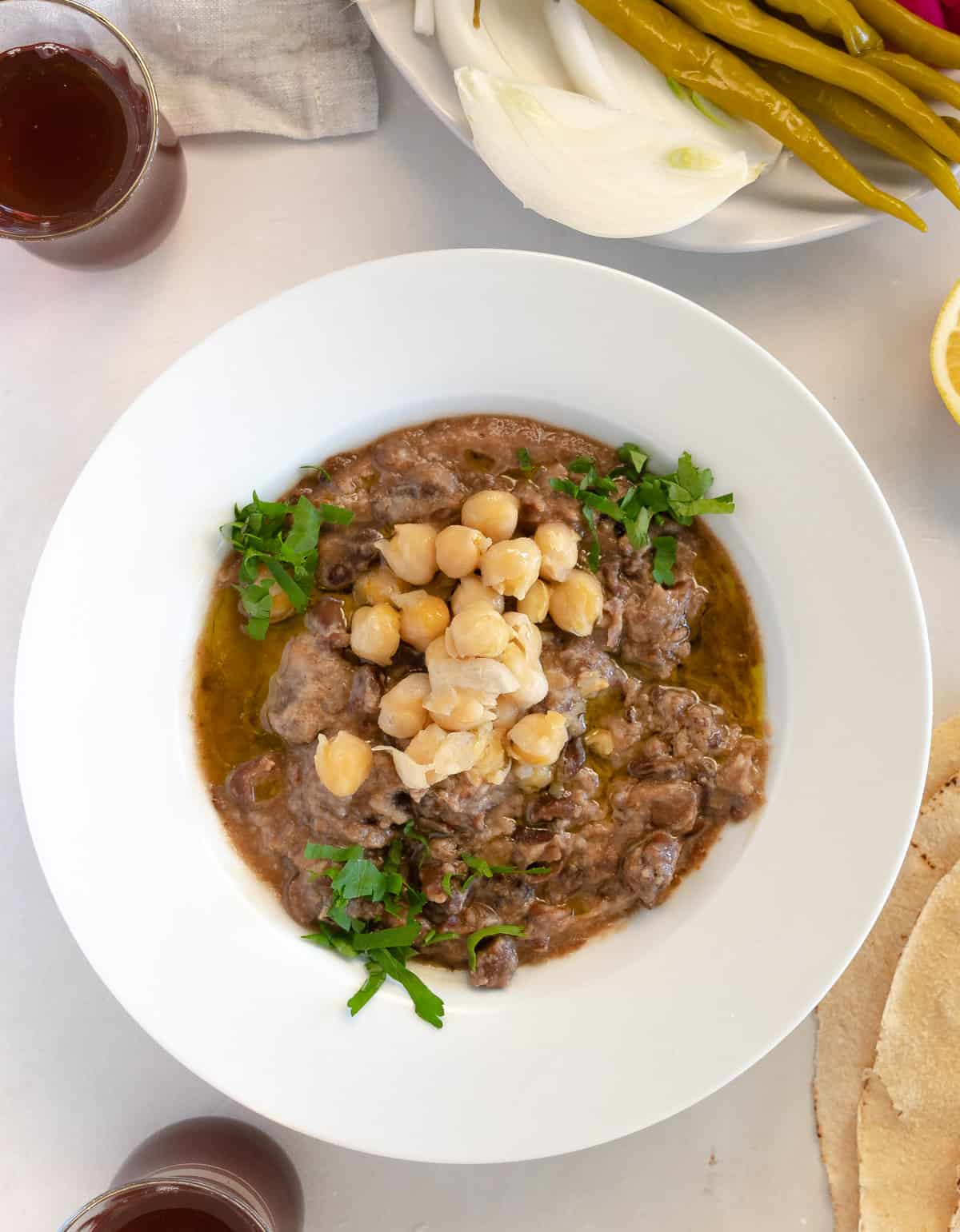 creamy brown faba beans garnished with chopped parsley and two cups of tea