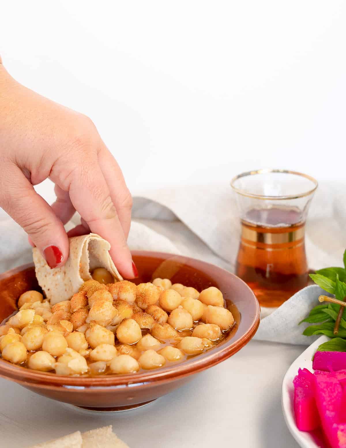 a female hand scooping chickpeas using flat bread