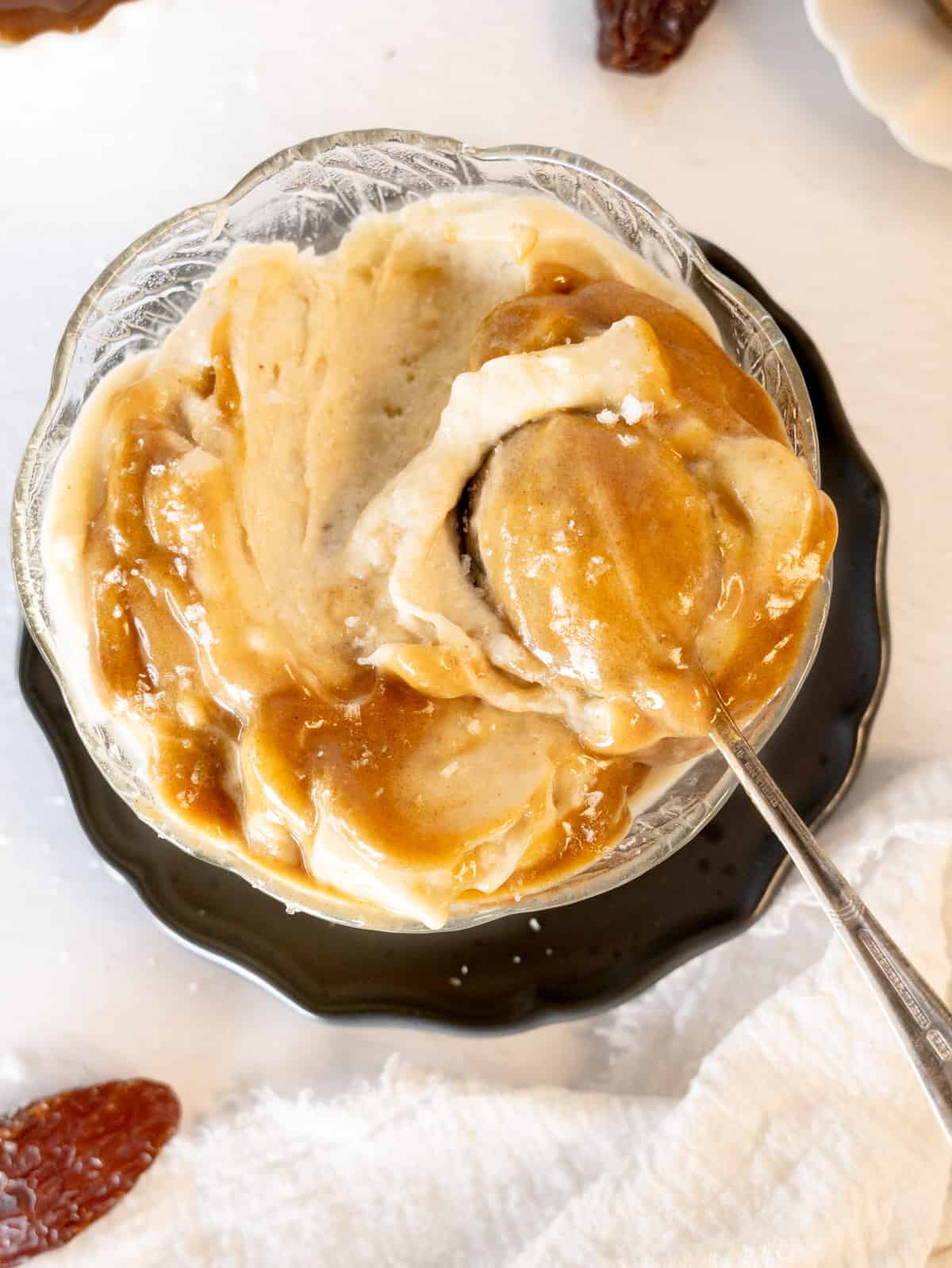 a glass bowl of caramel nice cream with a spoon in it