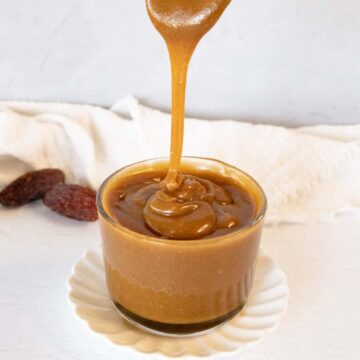 a spoon dripping light brown caramel sauce into a bowl