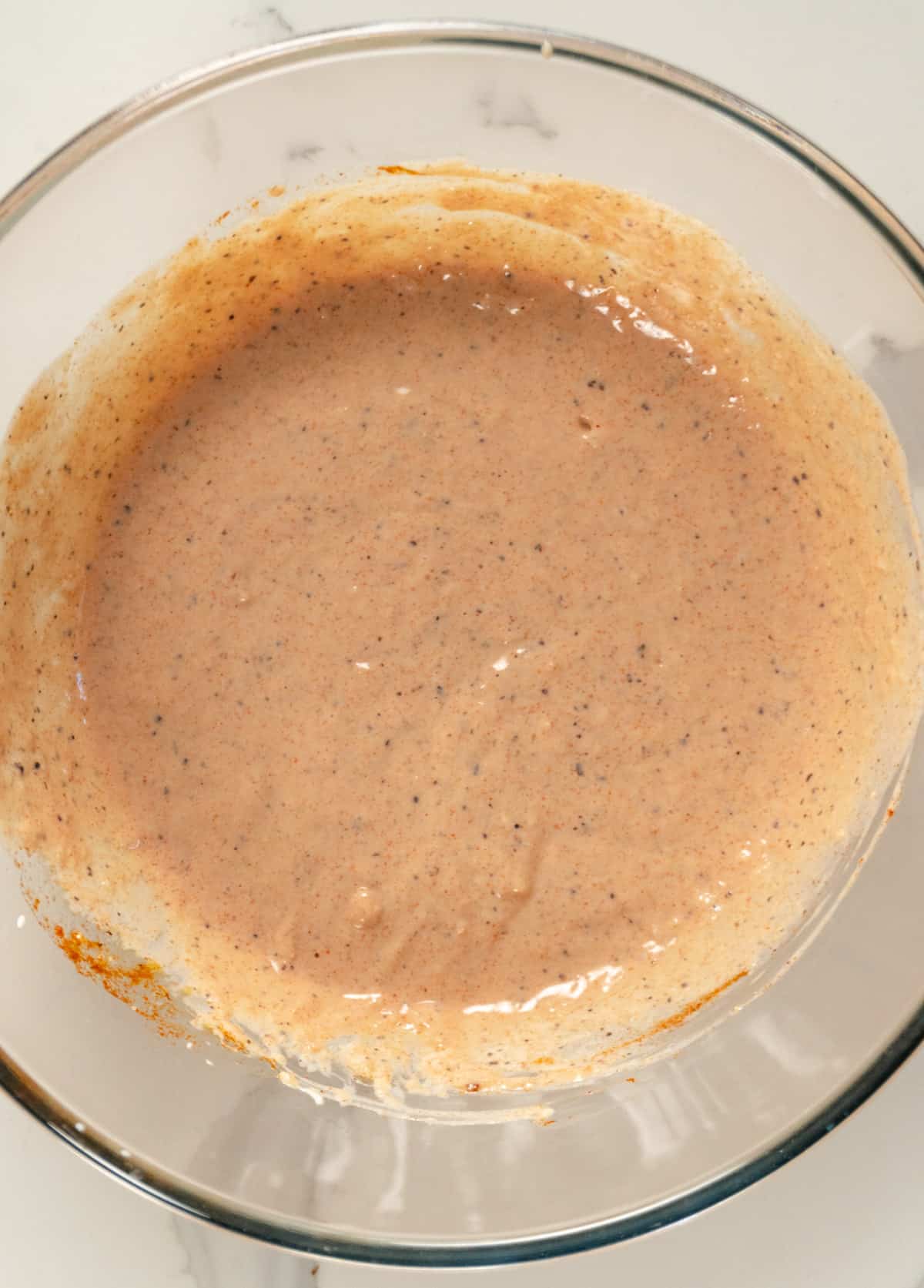 a pinkish sauce with dark specs through it in a glass bowl