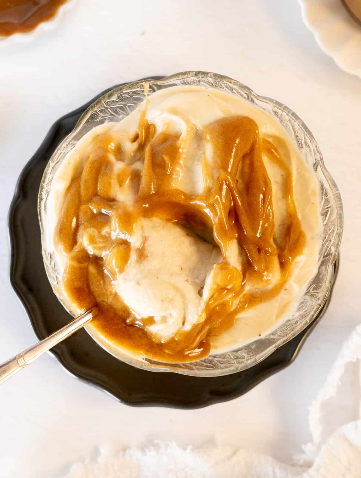 a spoon in a bowl of ice cream topped with caramel