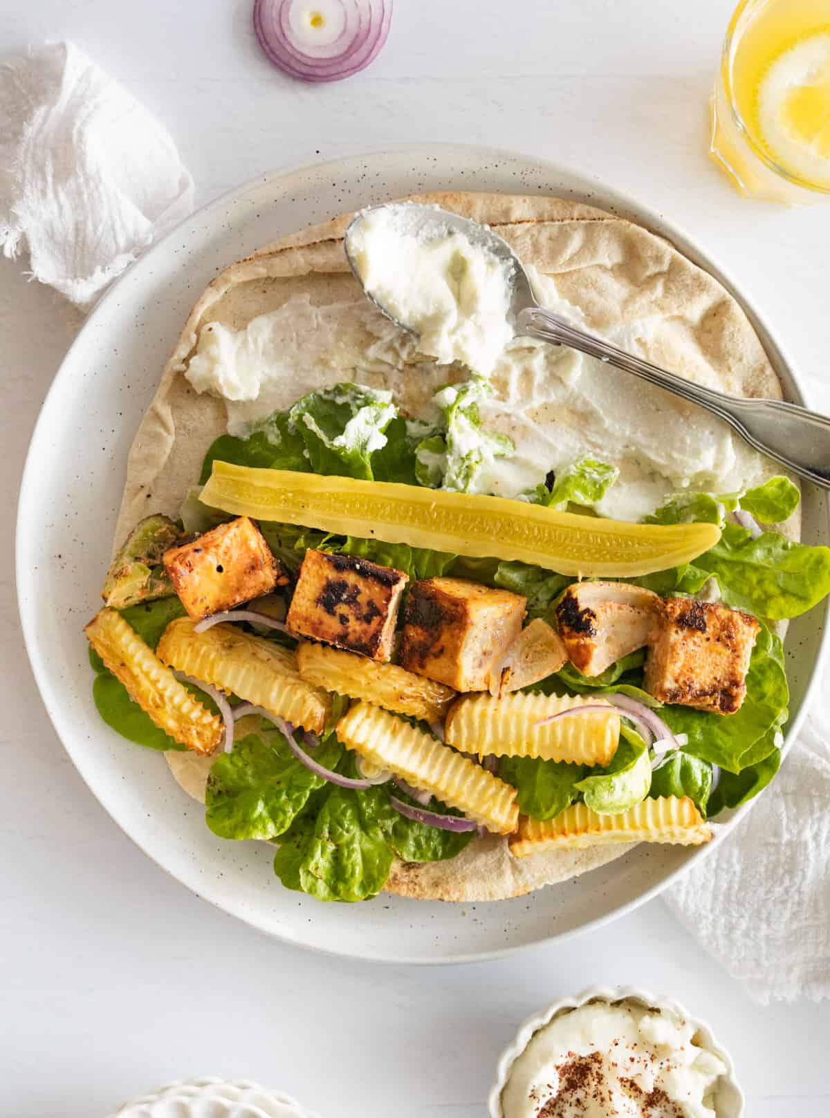 pieces of grilled tofu, with lettuce, fries, pickles cucumber and garlic sauce in pita bread