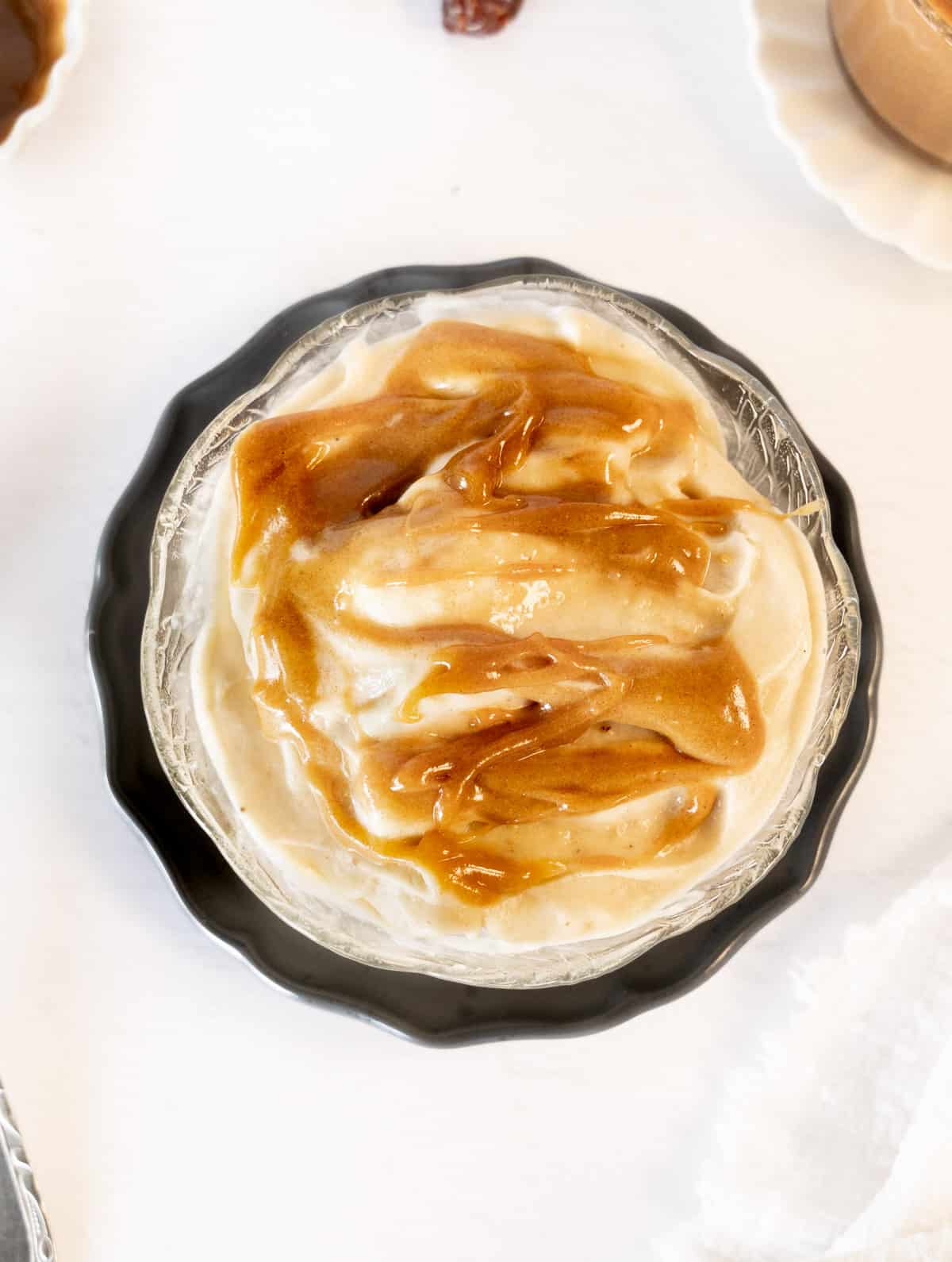 light brown caramel sauce on whiteish nice cream in a bowl