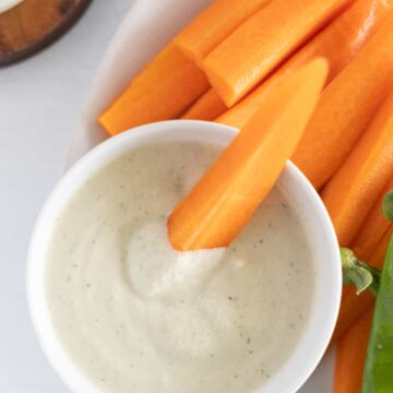a carrot stick dipped in white sauce