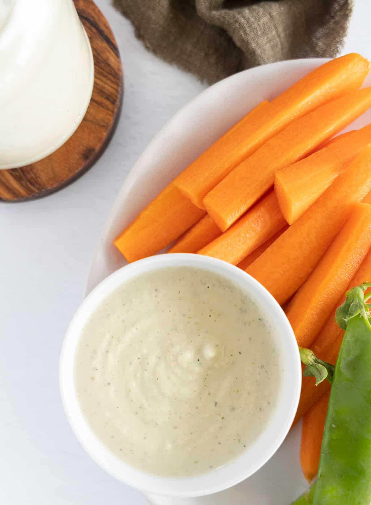 carrot stick on the side of a bowl of white sauce