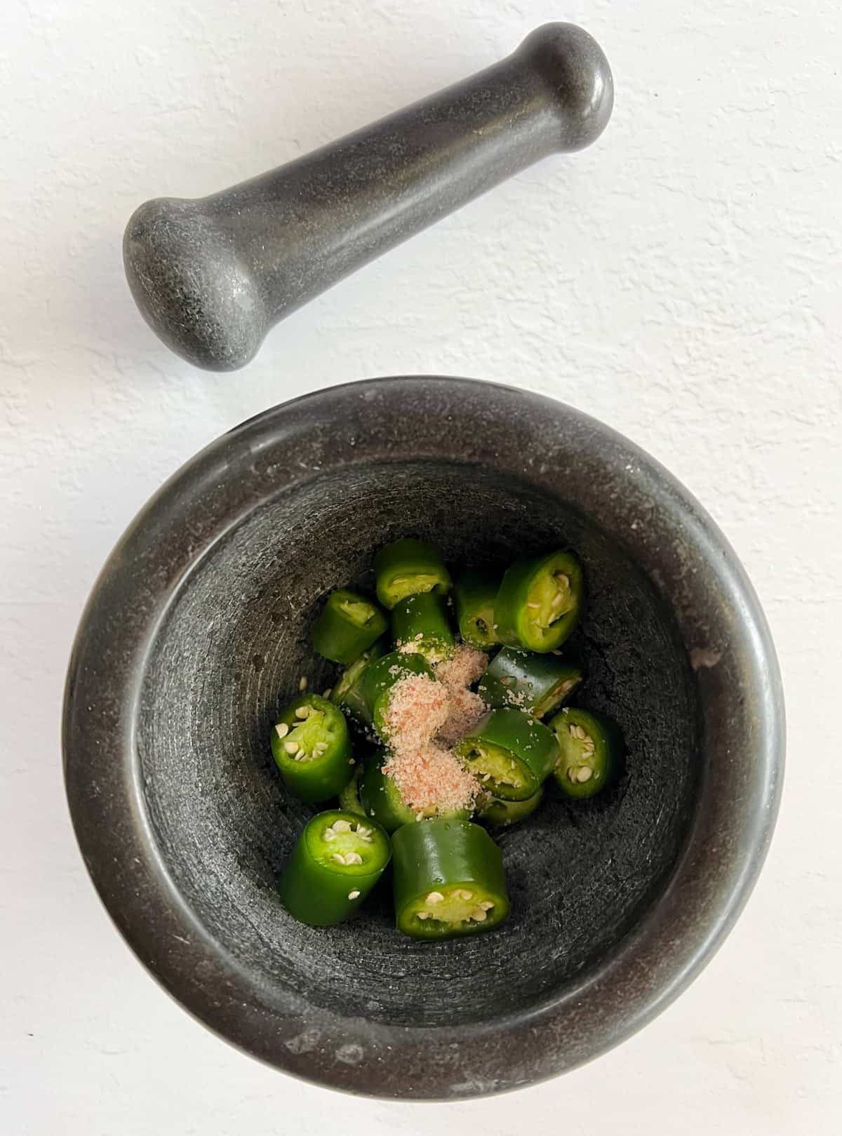 chopped green chili with salt in a pestle and mortar 