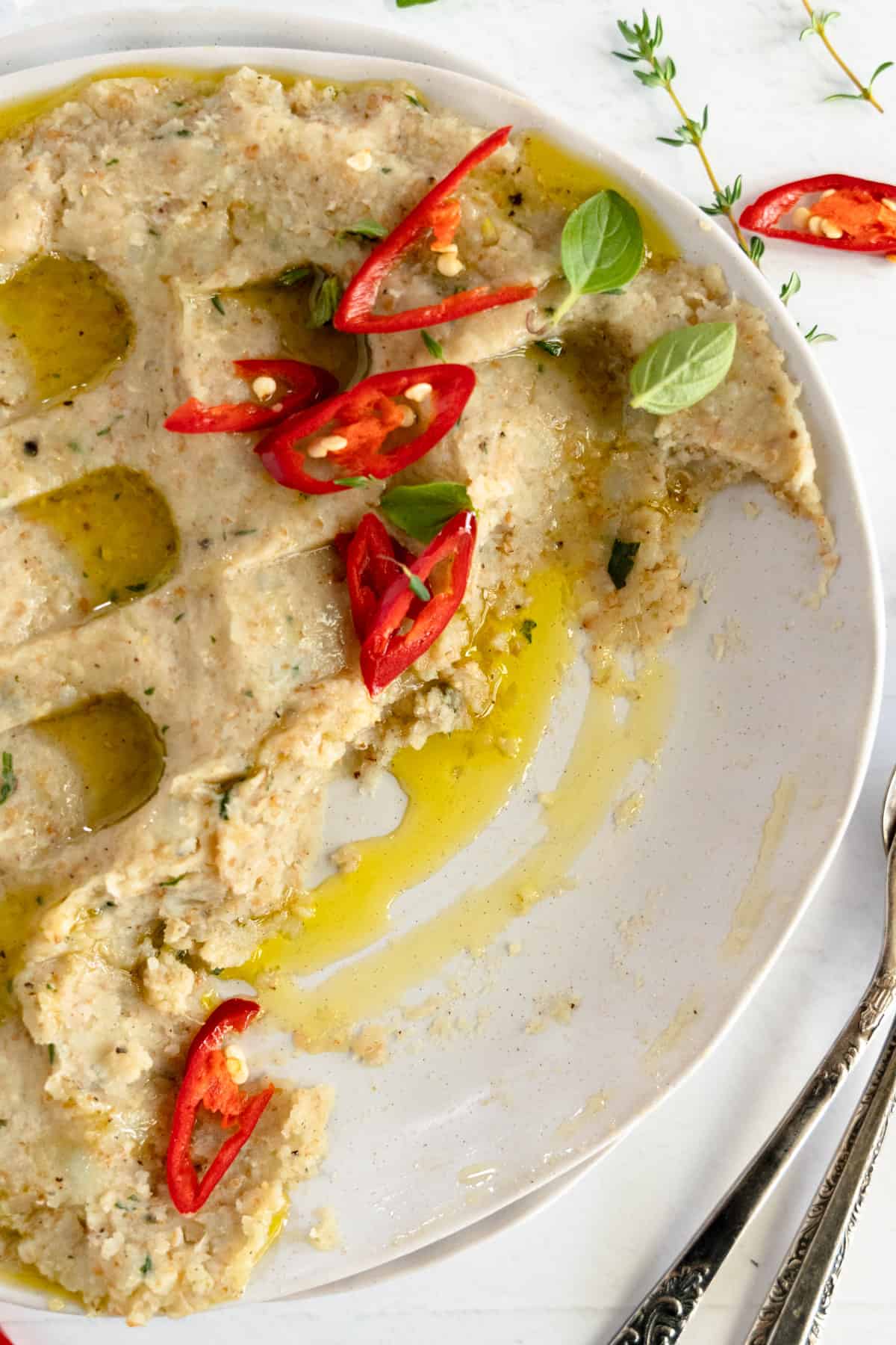 a white plate with potato and bulgur past with some of it smeared off