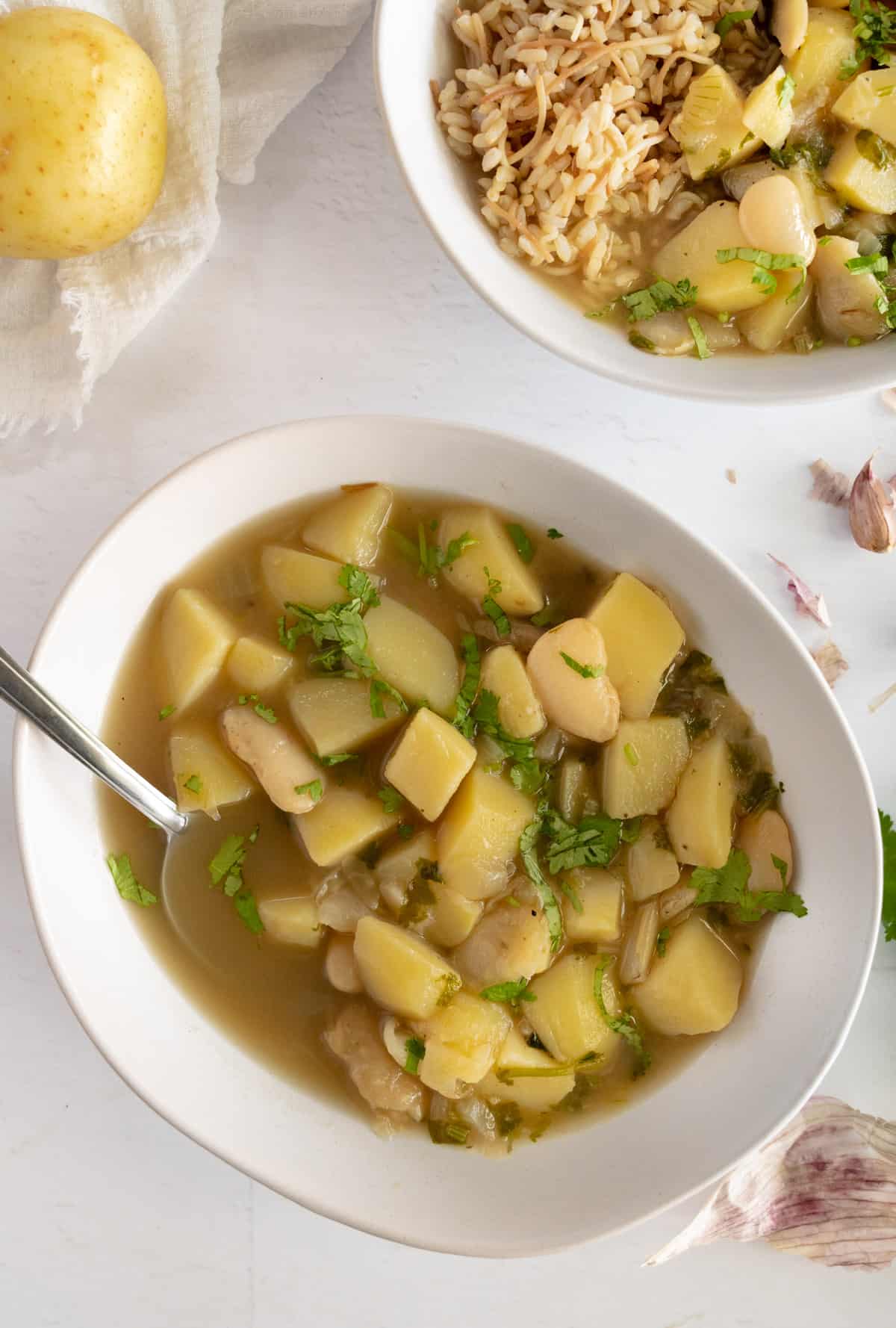 a white bowl of cooked potatoes with green herbs