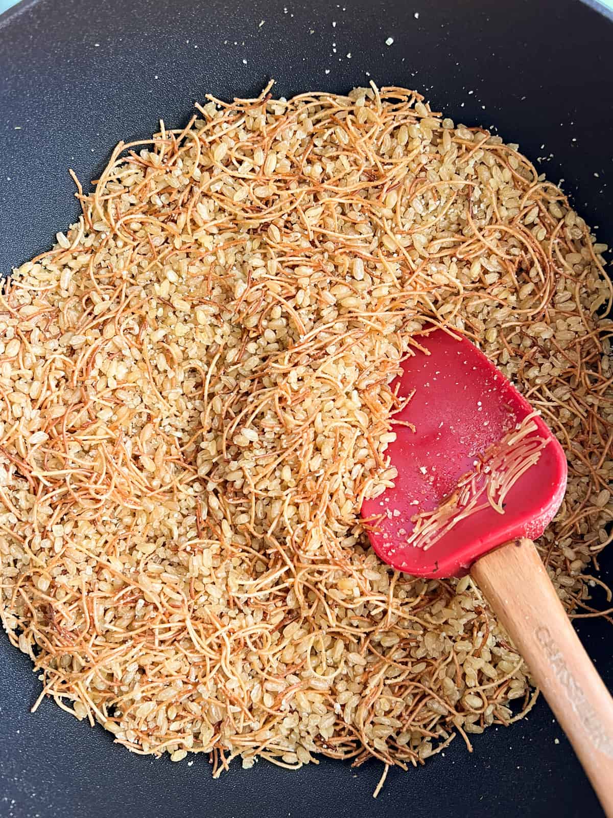 mixing bulgur with caramelized vermicelli in a black pot