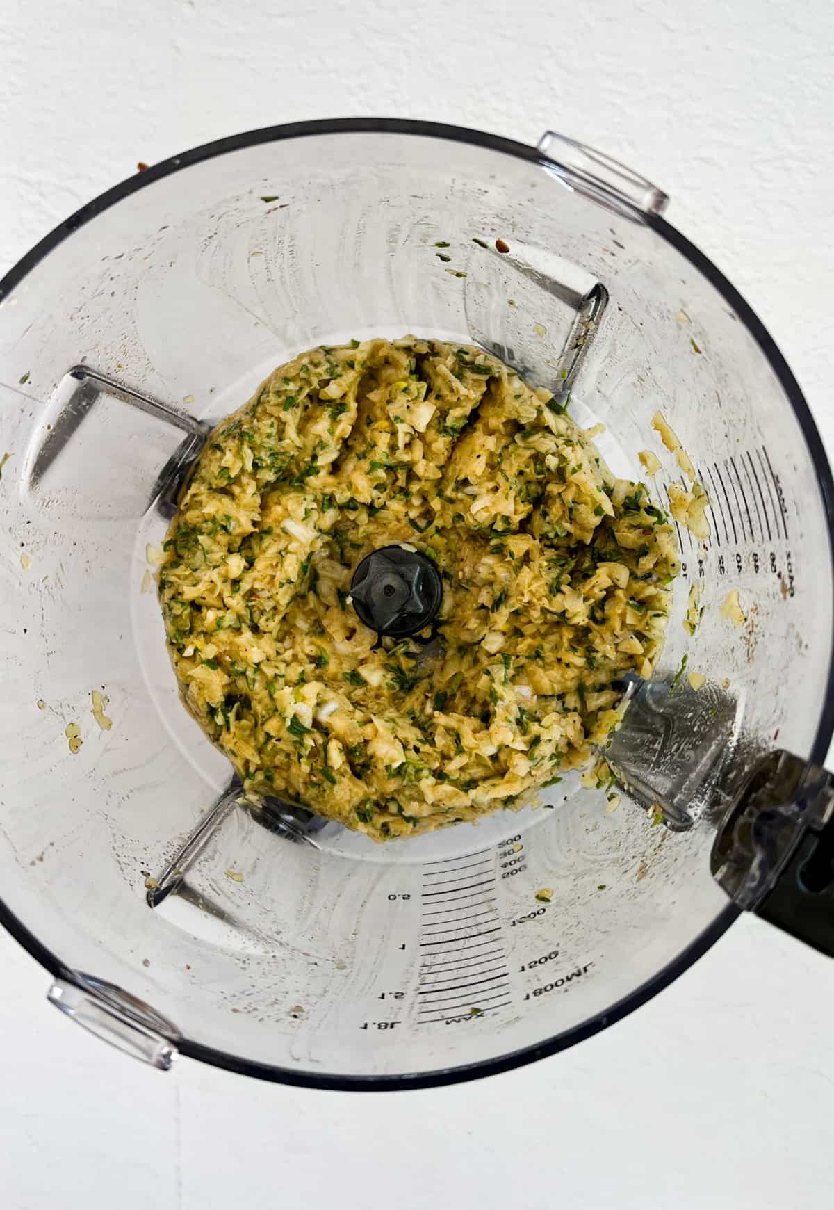 blended onion and herbs in a food processor bowl
