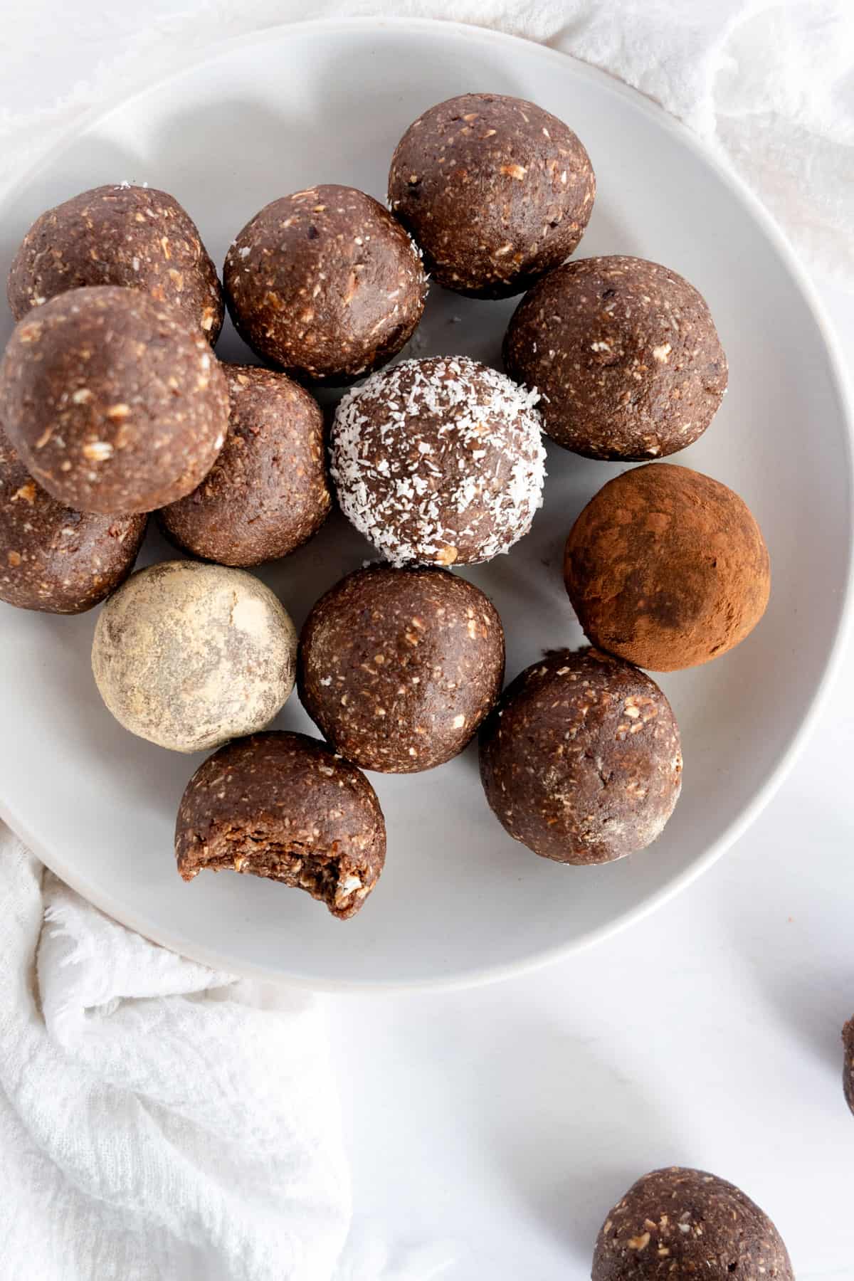 a white plate full of brown bliss balls