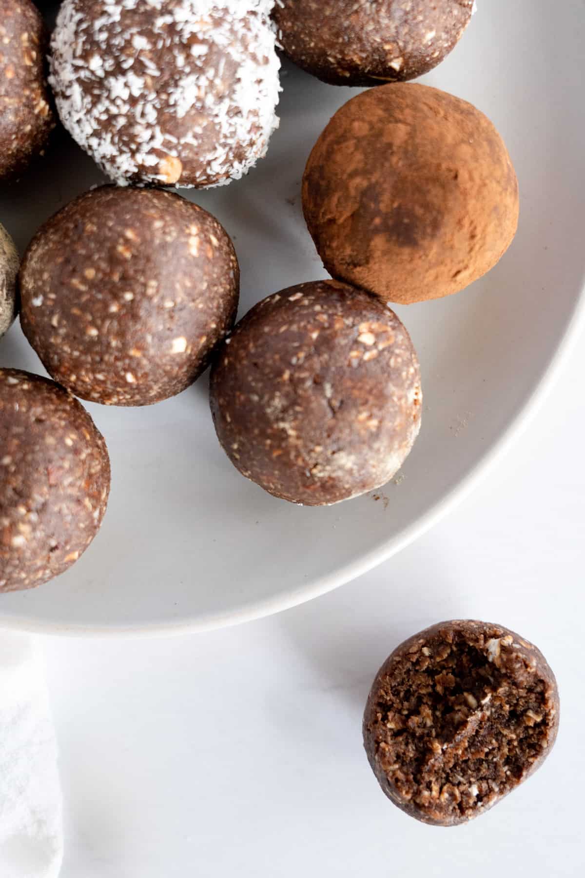 brown chocolate balls on a white plate with one on the side and a bit missing from it