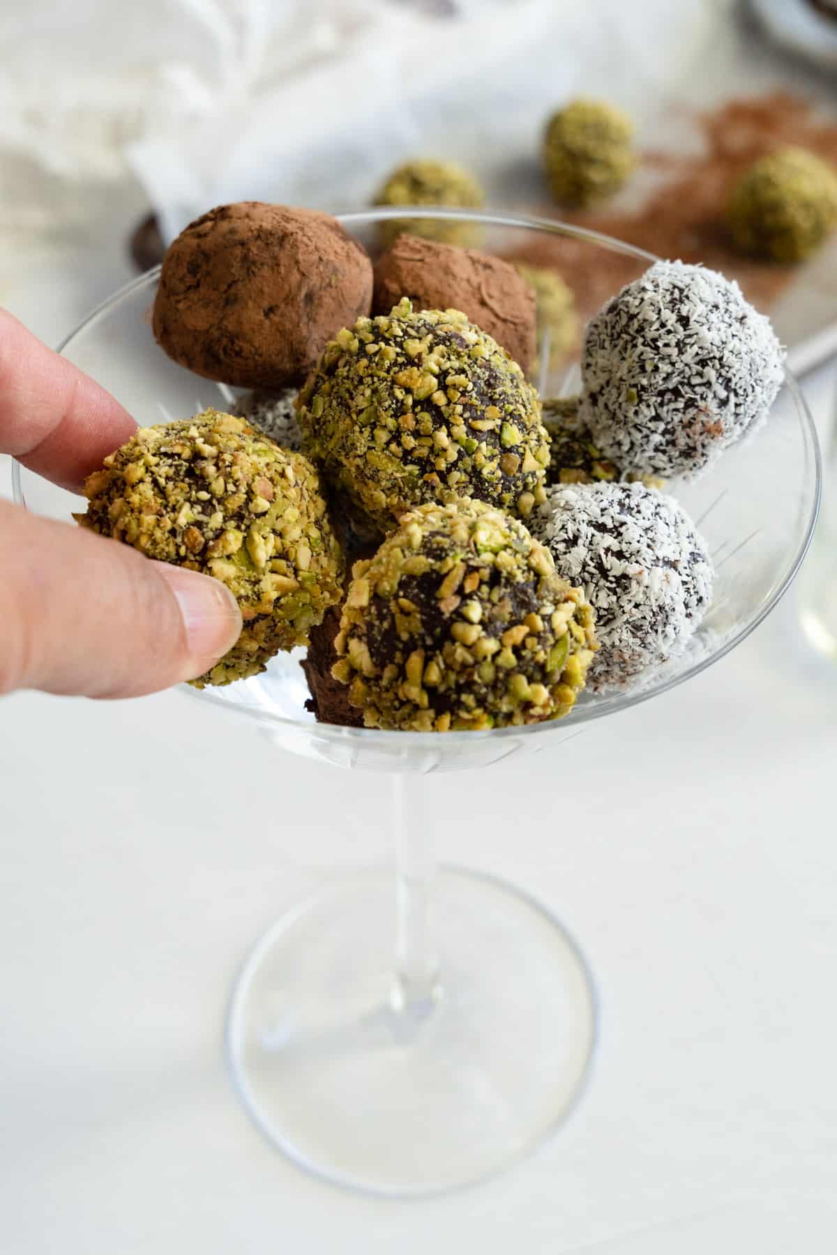 fingers picking out one truffle ball out of a champagne glass