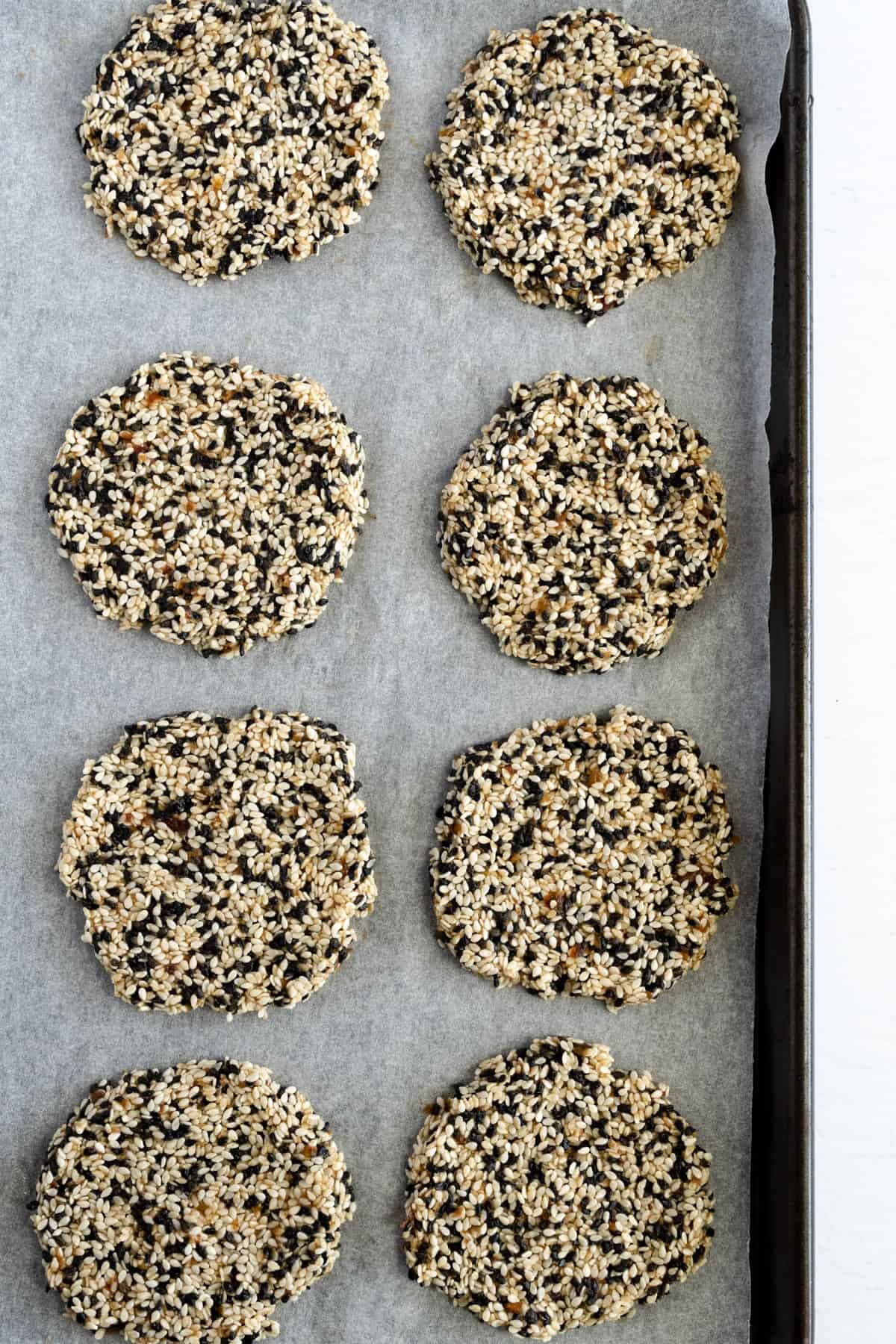 8 unbaked sesame cookies on a baking tray