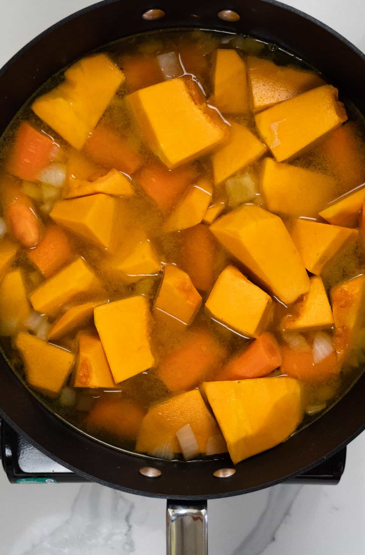 chopped carrots and pumpkin with water in a black pot
