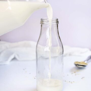 pouring white milk into a glass bottle