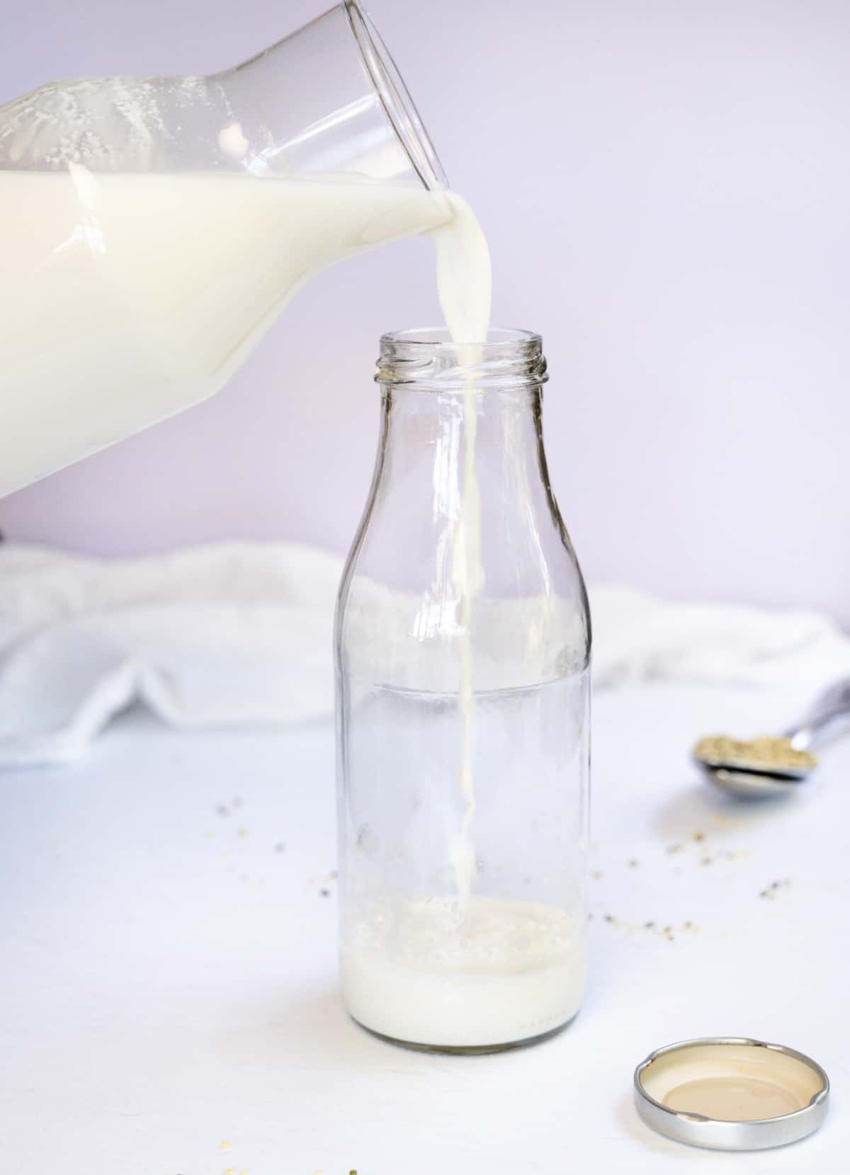 pouring white milk into a glass bottle