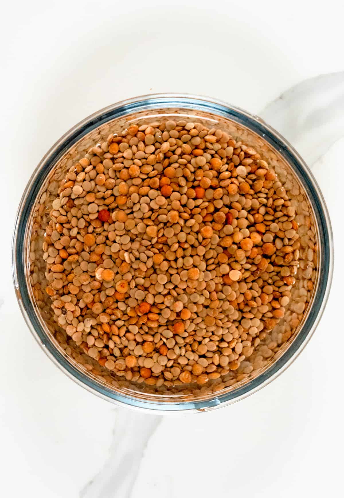 a glass bowl of lentils in water