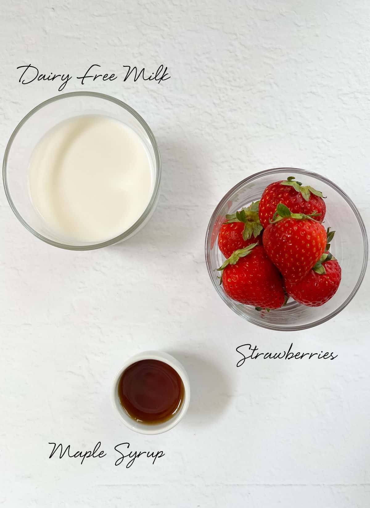 strawberries, milk and maple syrup in white bowls
