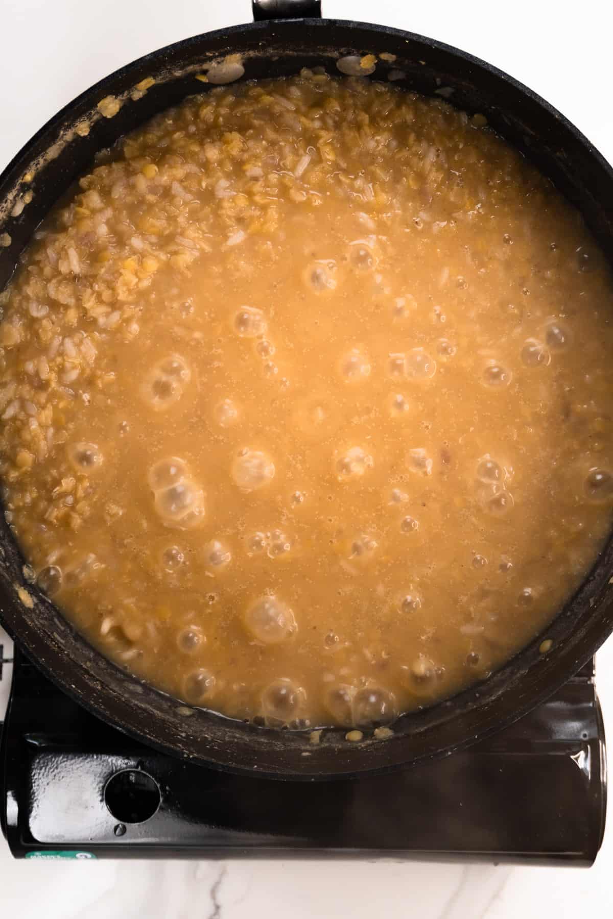 red lentils simmering with bubbles in a black pan