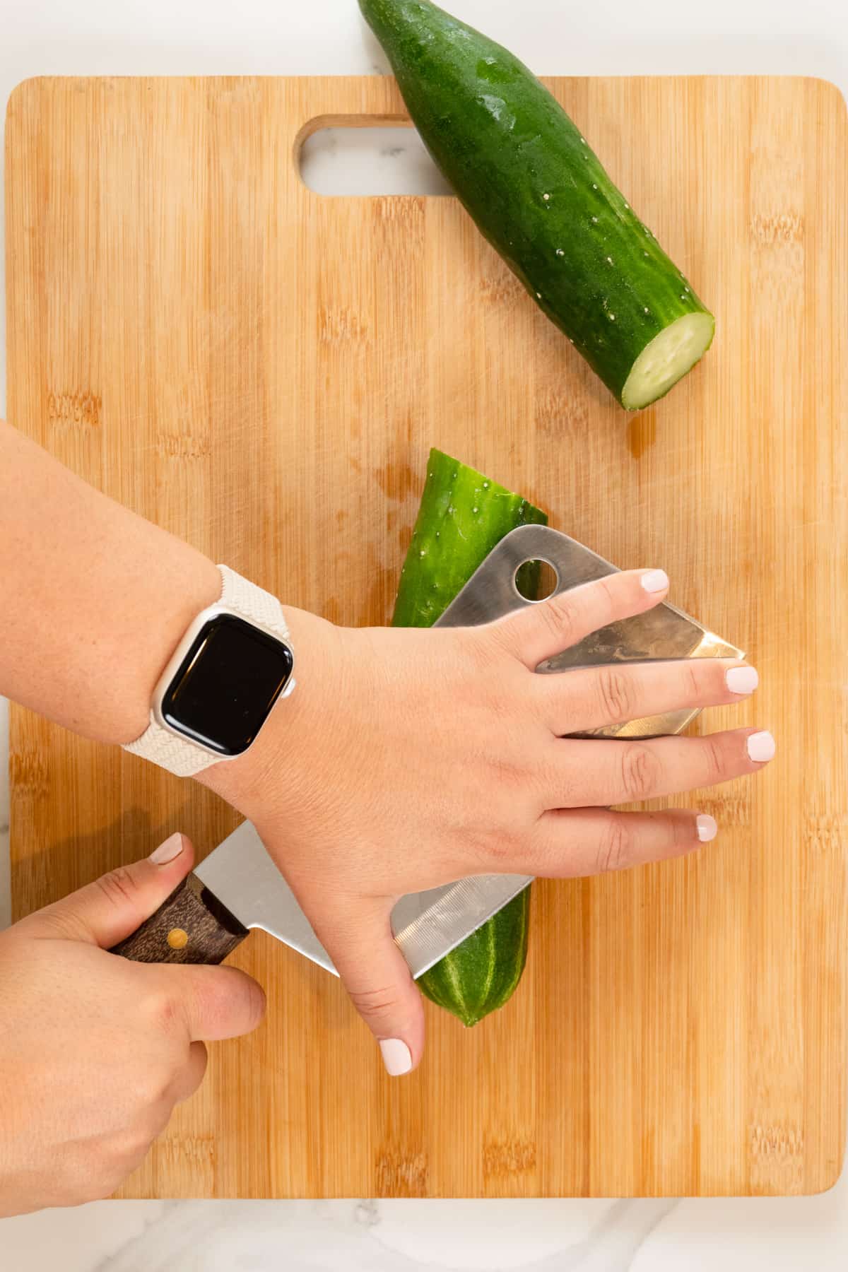 female hands using a cleaver to smack cucumber